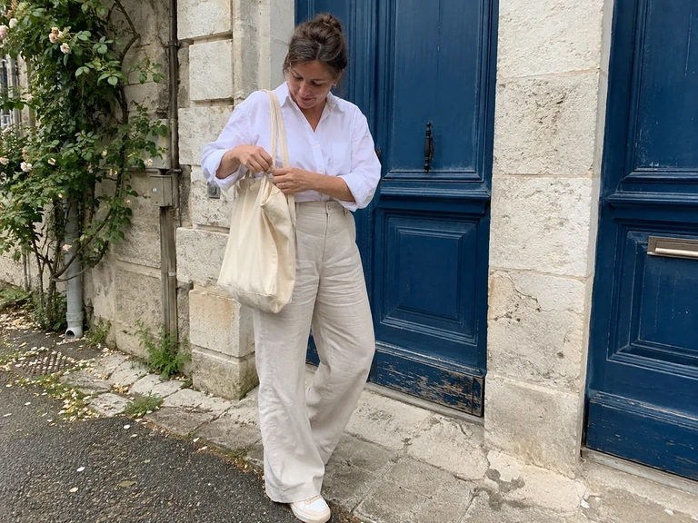 Une femme associe une chemise blanche à un pantalon écru