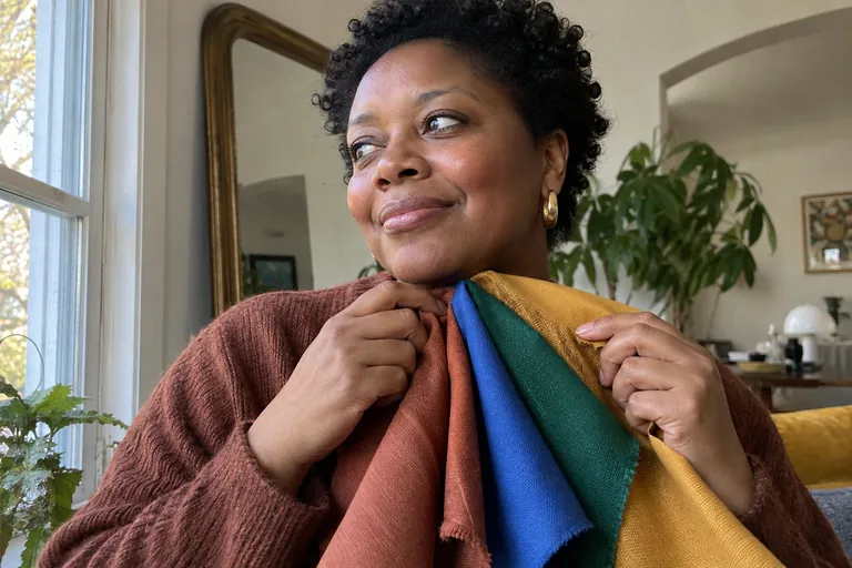 Une femme compare des échantillons de tissu de différentes couleurs près de son visage
