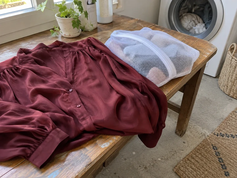 Une blouse en viscose repose à côté d’un filet de lavage