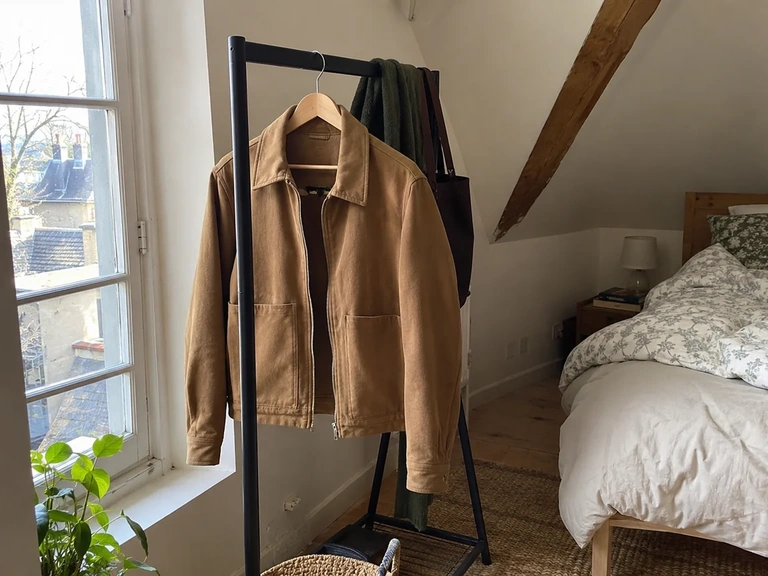 Une veste sèche reste seule sur un cintre près d’une fenêtre