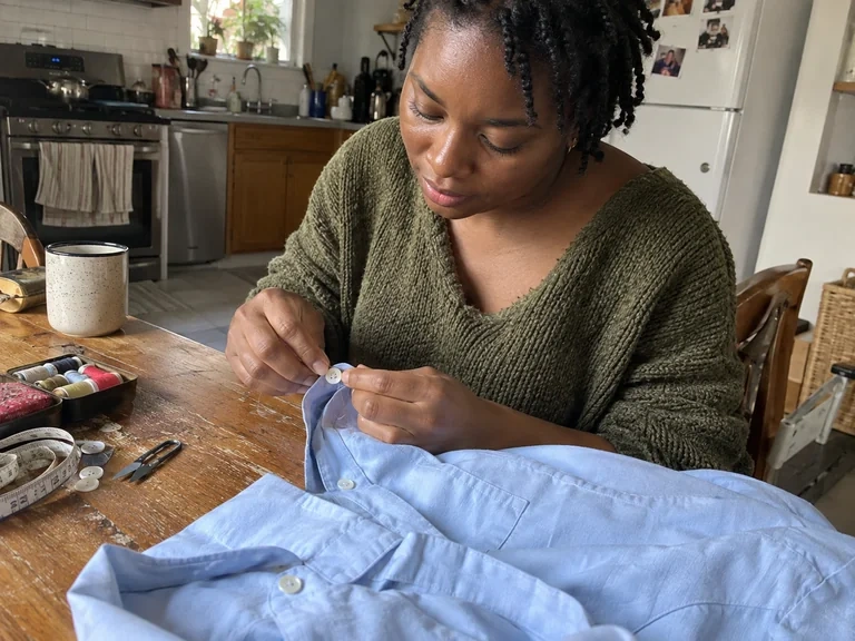 Un bouton de chemise est réparé à une table de cuisine
