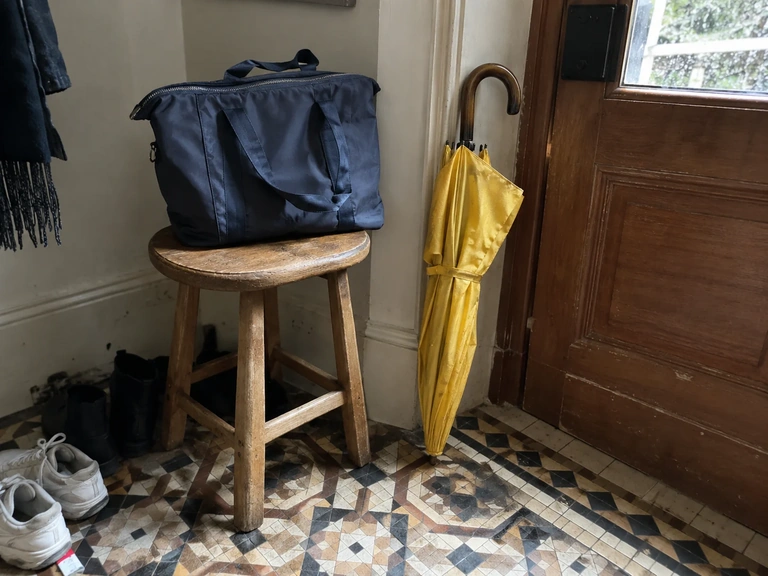 Un sac fermé et un parapluie dans une entrée