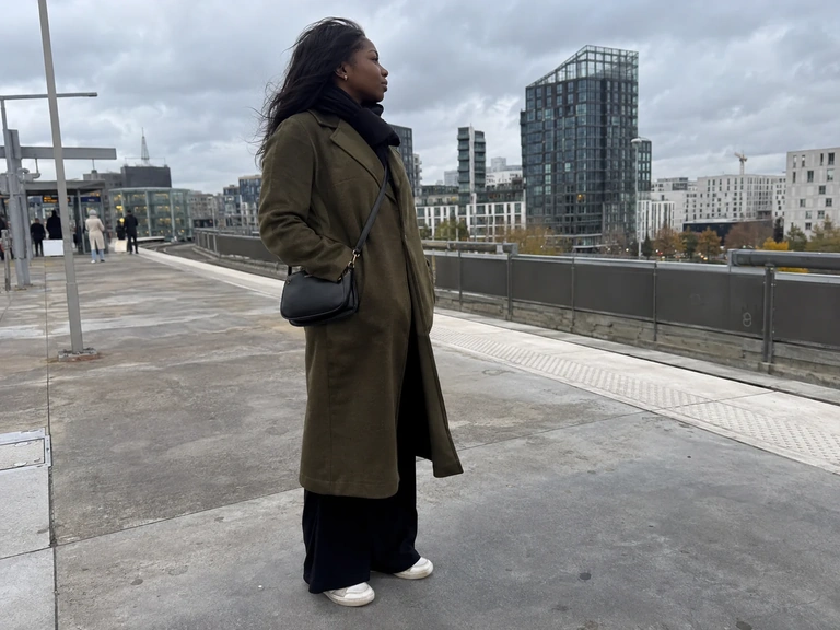 Un manteau fermé et un sac près du corps sur un quai