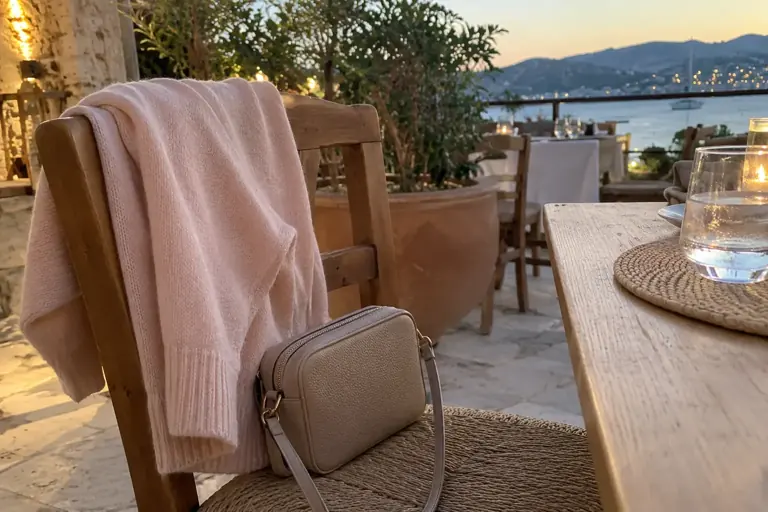 Un cardigan et un petit sac sont préparés sur une chaise de terrasse
